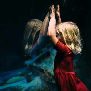 girl leaning on glass fish tank raising her two hands